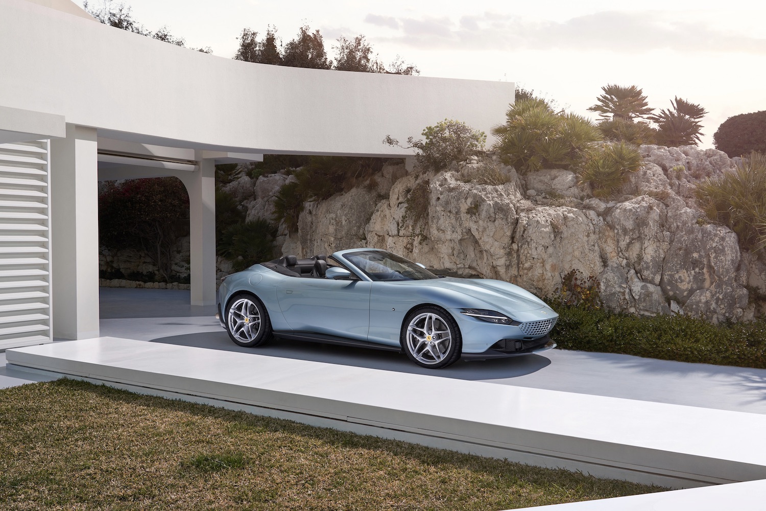 2024 Ferrari Roma front end angle from driver's side parked in front of house with cliff in the back.