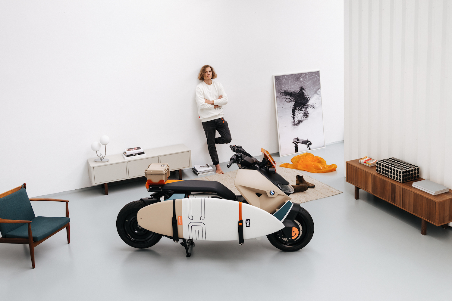 BMW CE 04 Vagabund Moto Concept parked in front of furniture in a studio with a man looking at the scooter.
