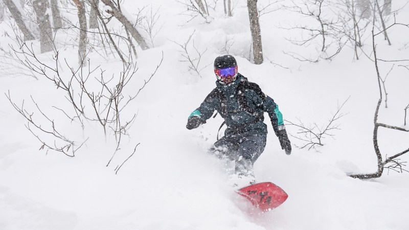 Person in full gear snowboarding down a mountainside. 