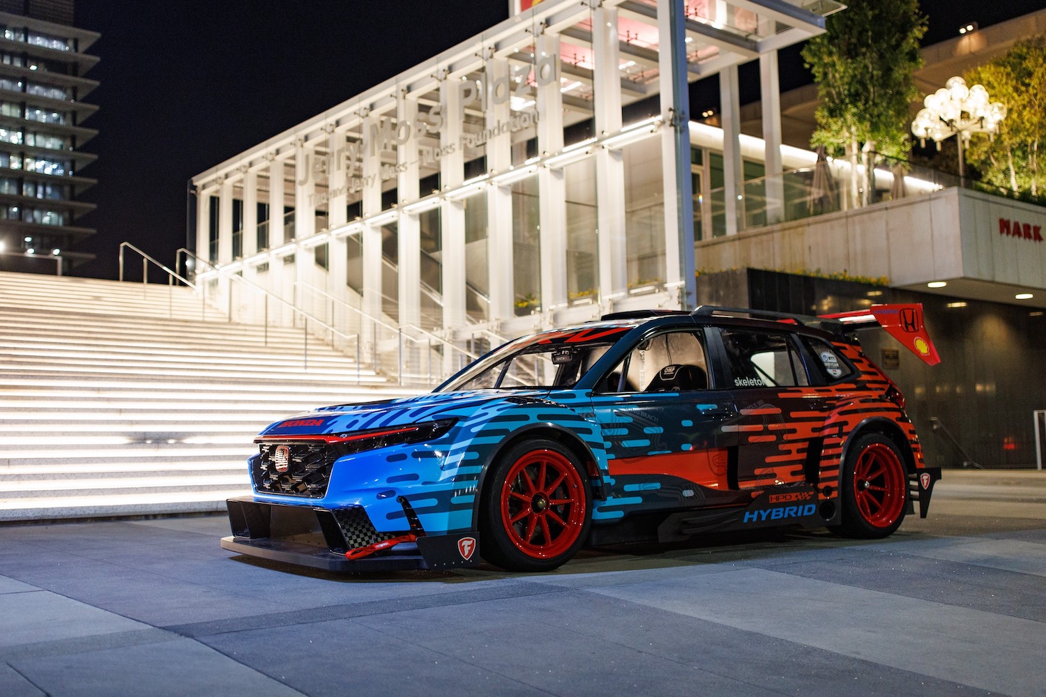 Front-end profile of the Honda CR-V Hybrid Racer from he driver's side parked in front of white stairs at night.