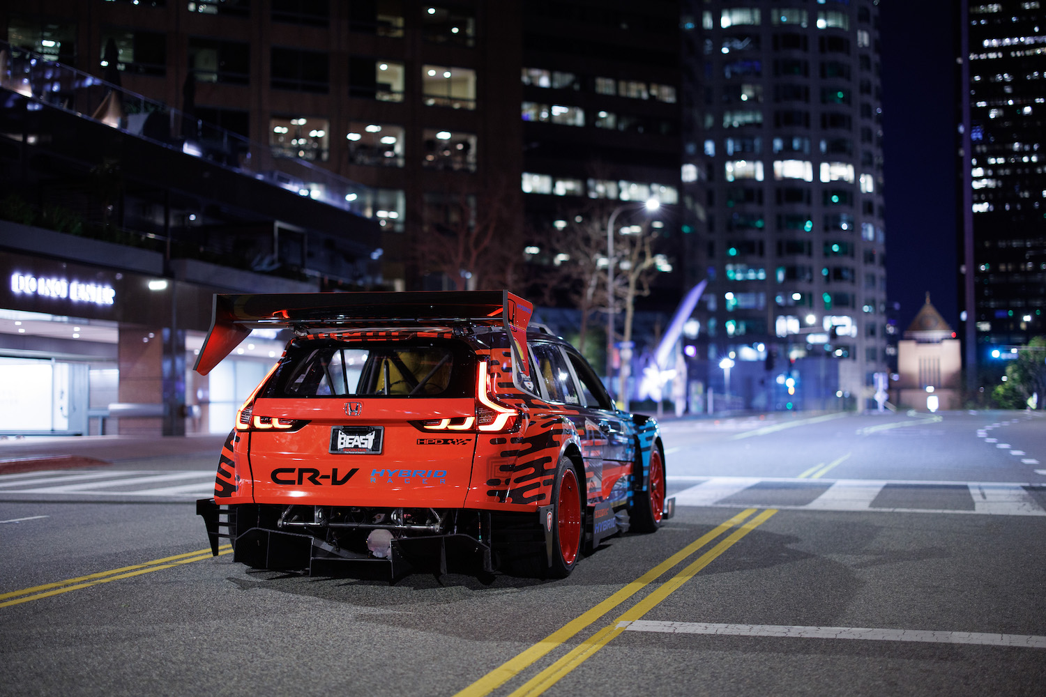 Honda CR-V Hybrid Racer rear end angle front passenger's side parked in the middle of the road at night.