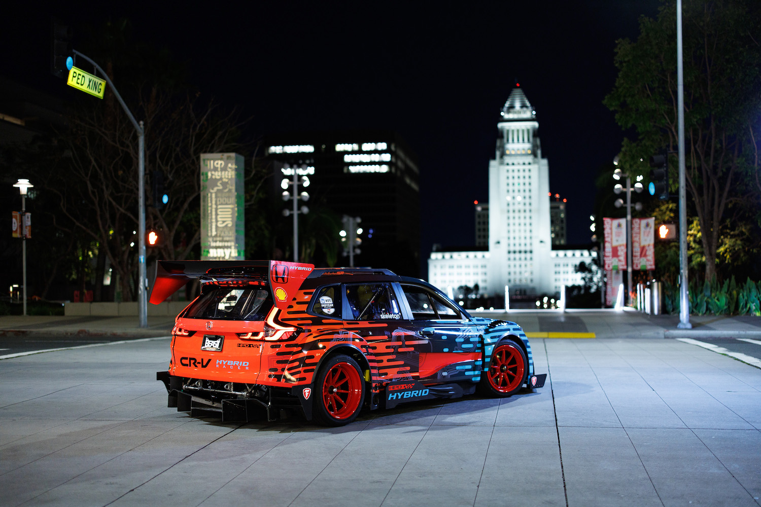 Rear end angle of the Honda CR-V Hybrid Racer from the passenger's side parked in front of a statute at night.