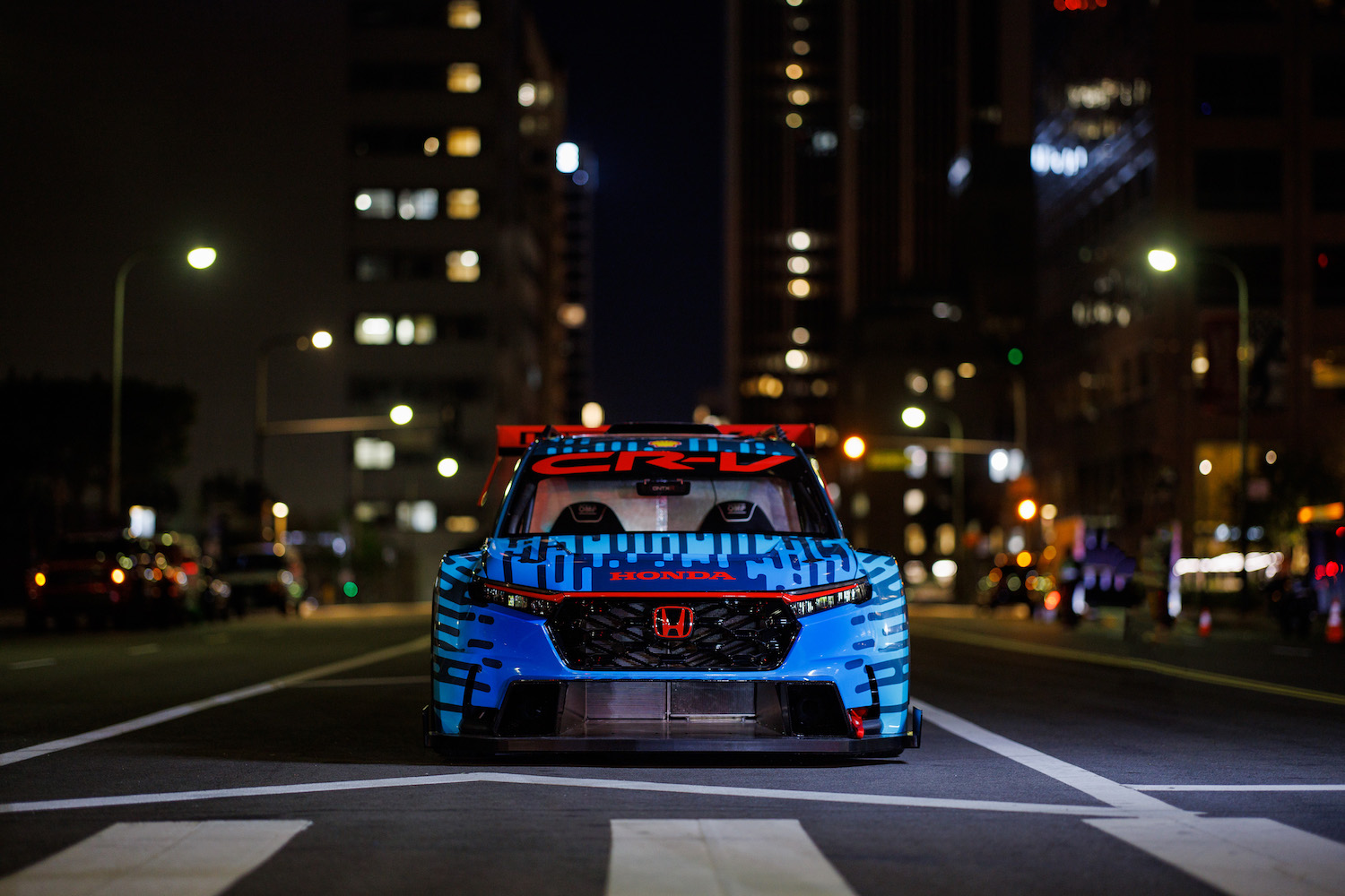 Close up of the Honda CR-V Hybrid Racer parked in the middle of the road at night.