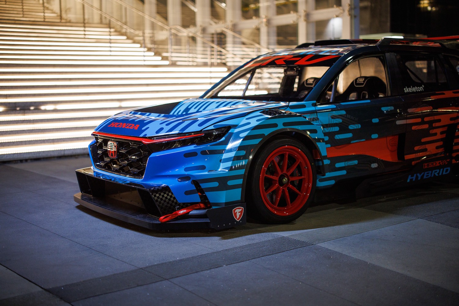 Close up of the front end of the Honda CR-V Hybrid Racer parked in front of white stairs at night.