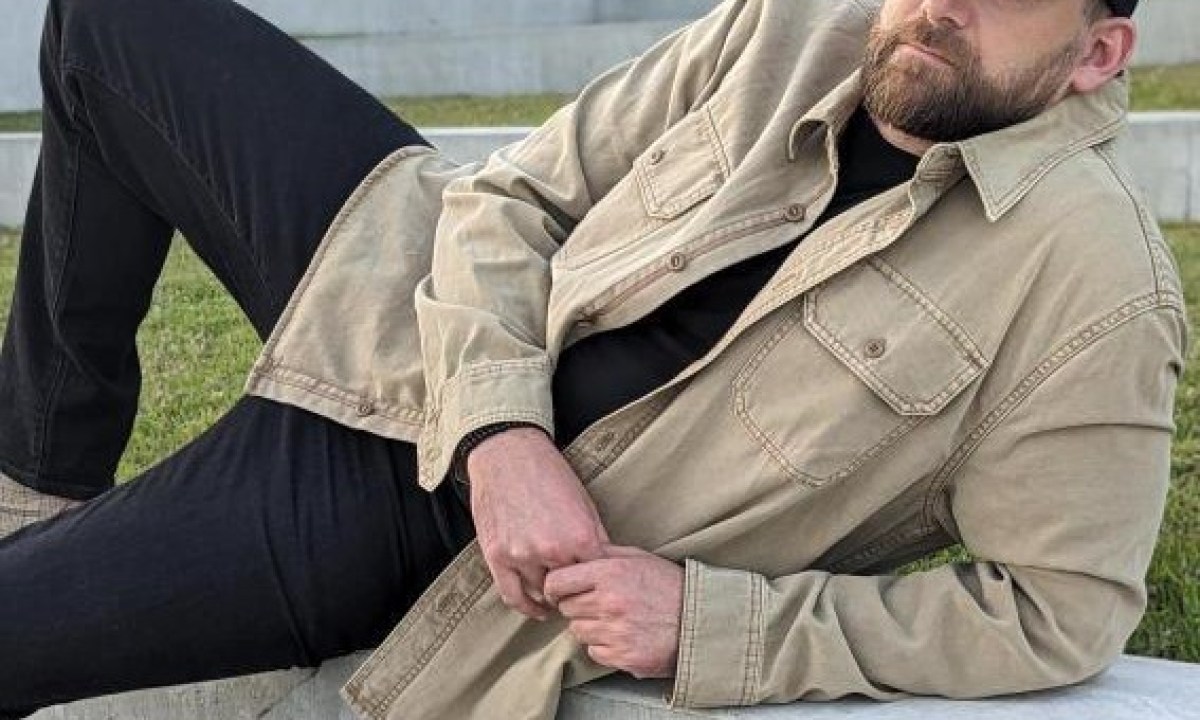 Man leaning in tan shacket and black denim