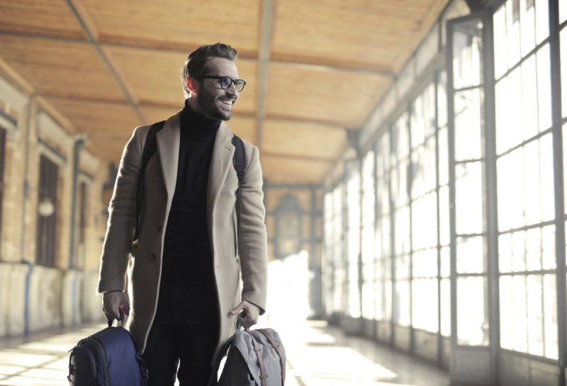 A person smiling, carrying their luggage, about to go on a trip.