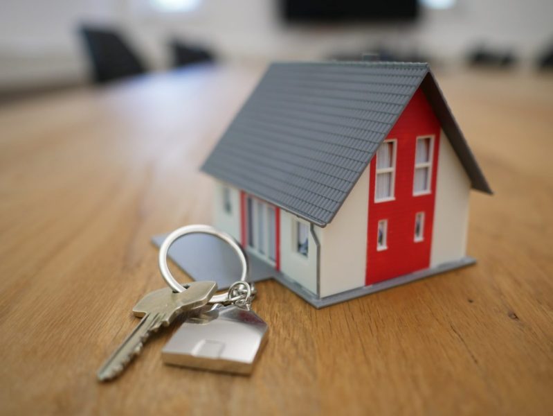 A small model house and a set of keys on a table.