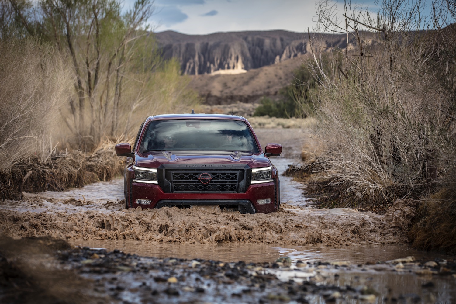 Close up of 2022 Nissan Frontier Pro-4X fording through deep water in the desert.