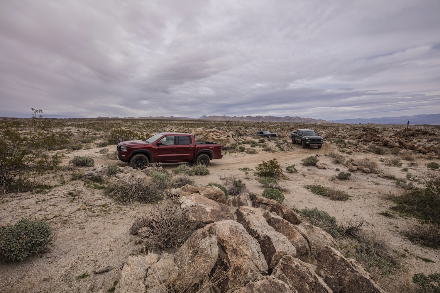 Side profile of the 2022 Nissan Frontier Pro-4X driving on a trail through the desert.