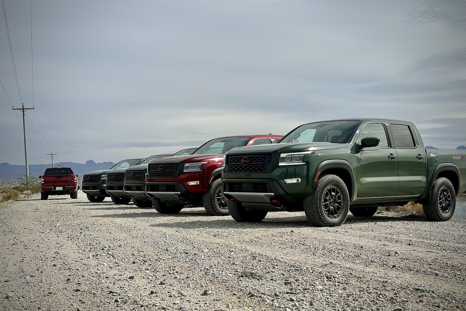 Front end angle of 2022 Nissan Frontier Pro-4X parked in a line on a dirt trail.