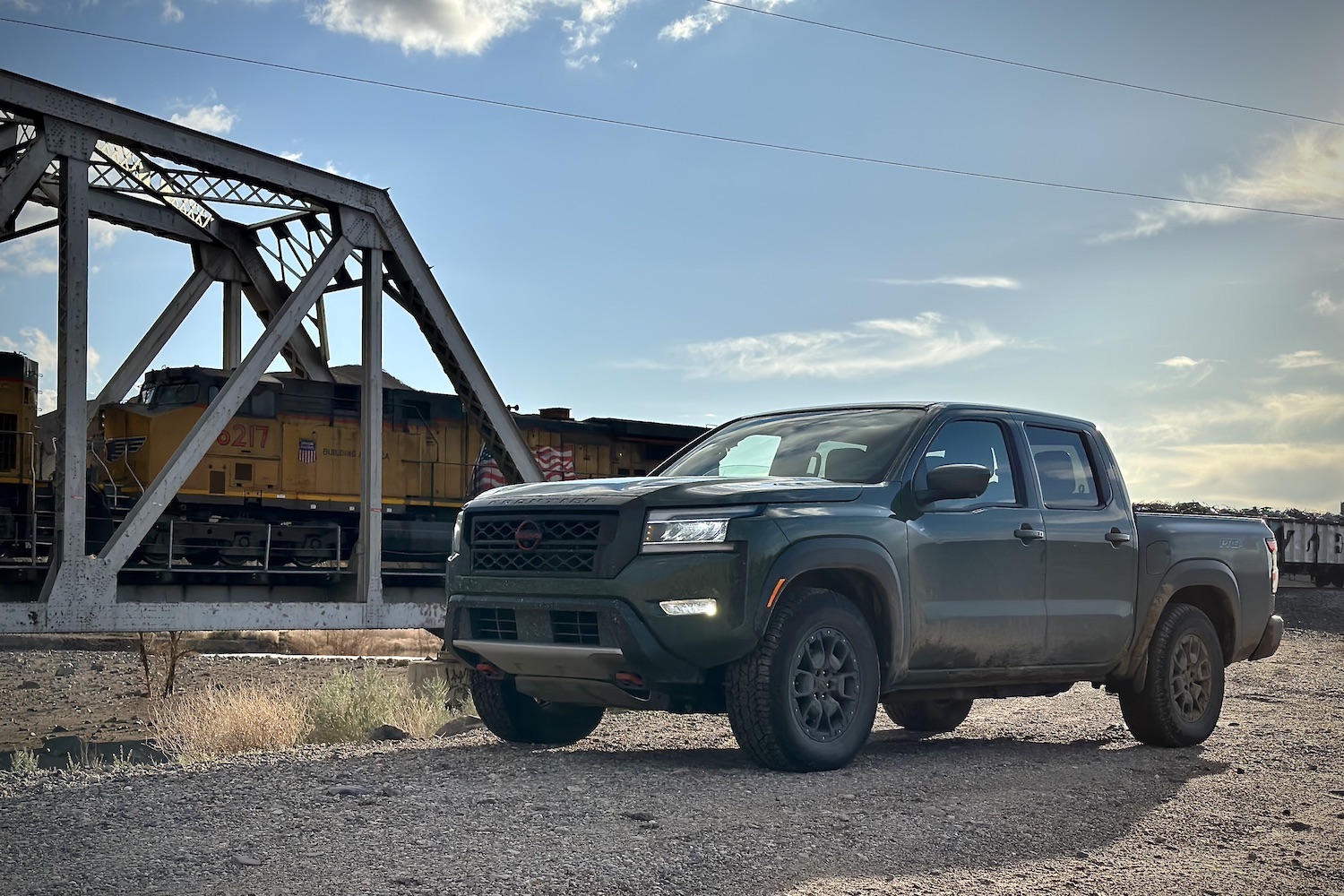 Front end angle of the 2022 Nissan Frontier Pro-4X with at train on a railroad track in the back.