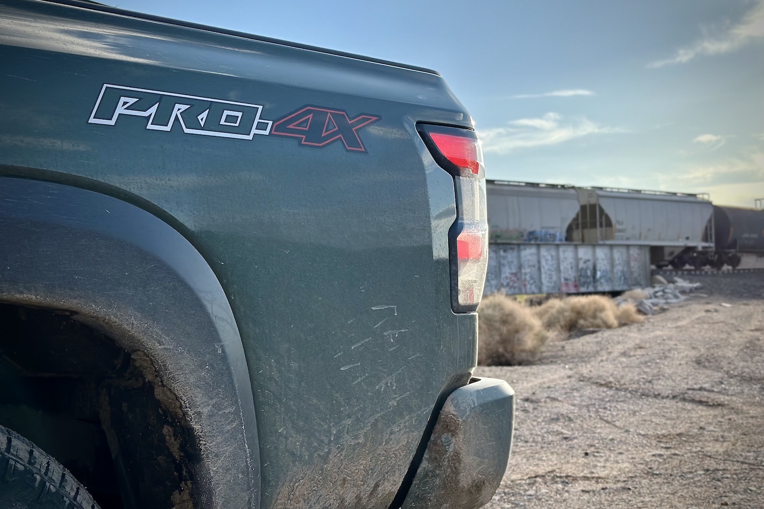 Close up of Pro-4X badge on the 2022 Nissan Frontier Pro-4X in front of a railroad track.