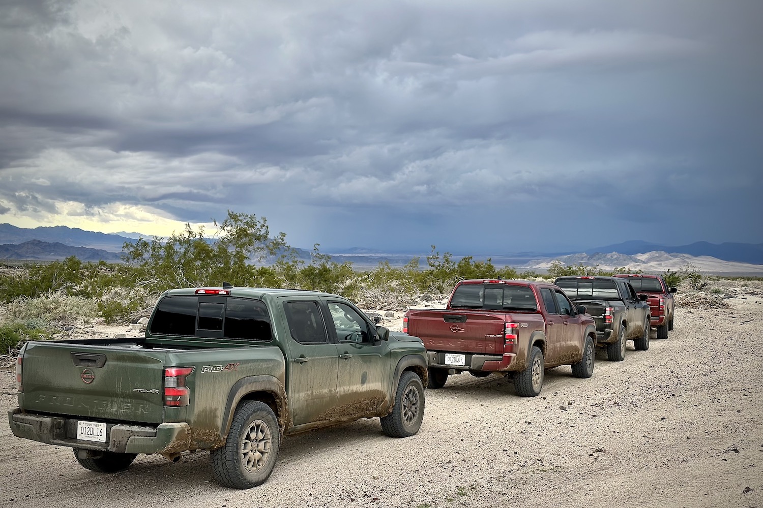 Rear end angle of the 2022 Nissan Frontier Pro-4X parked in a line with storm clouds in the back.
