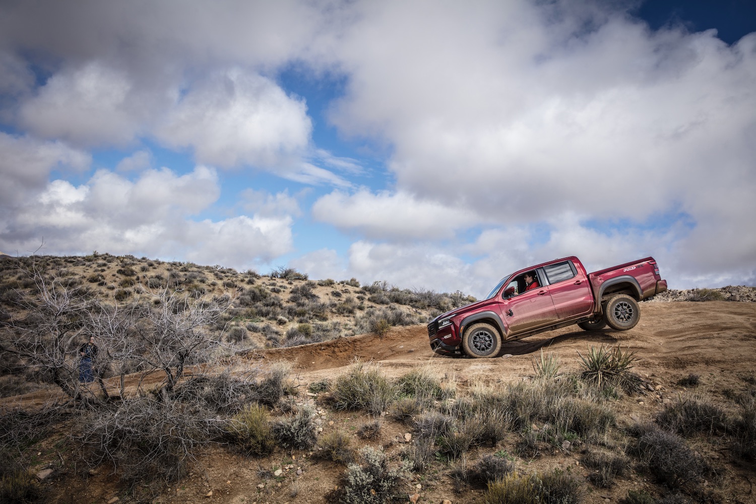 Side profile of the 2022 Nissan Frontier Pro-4X off-roading down a steep hill.