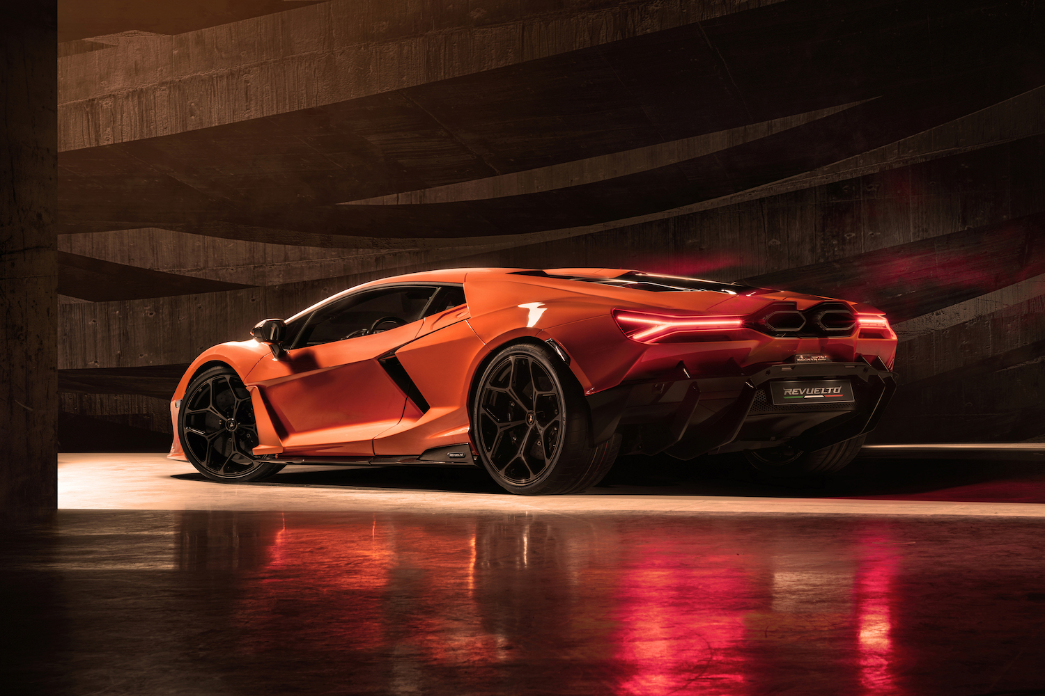 Rear end angle of the 2024 Lamborghini Revuelto from the driver's side parked in a studio.