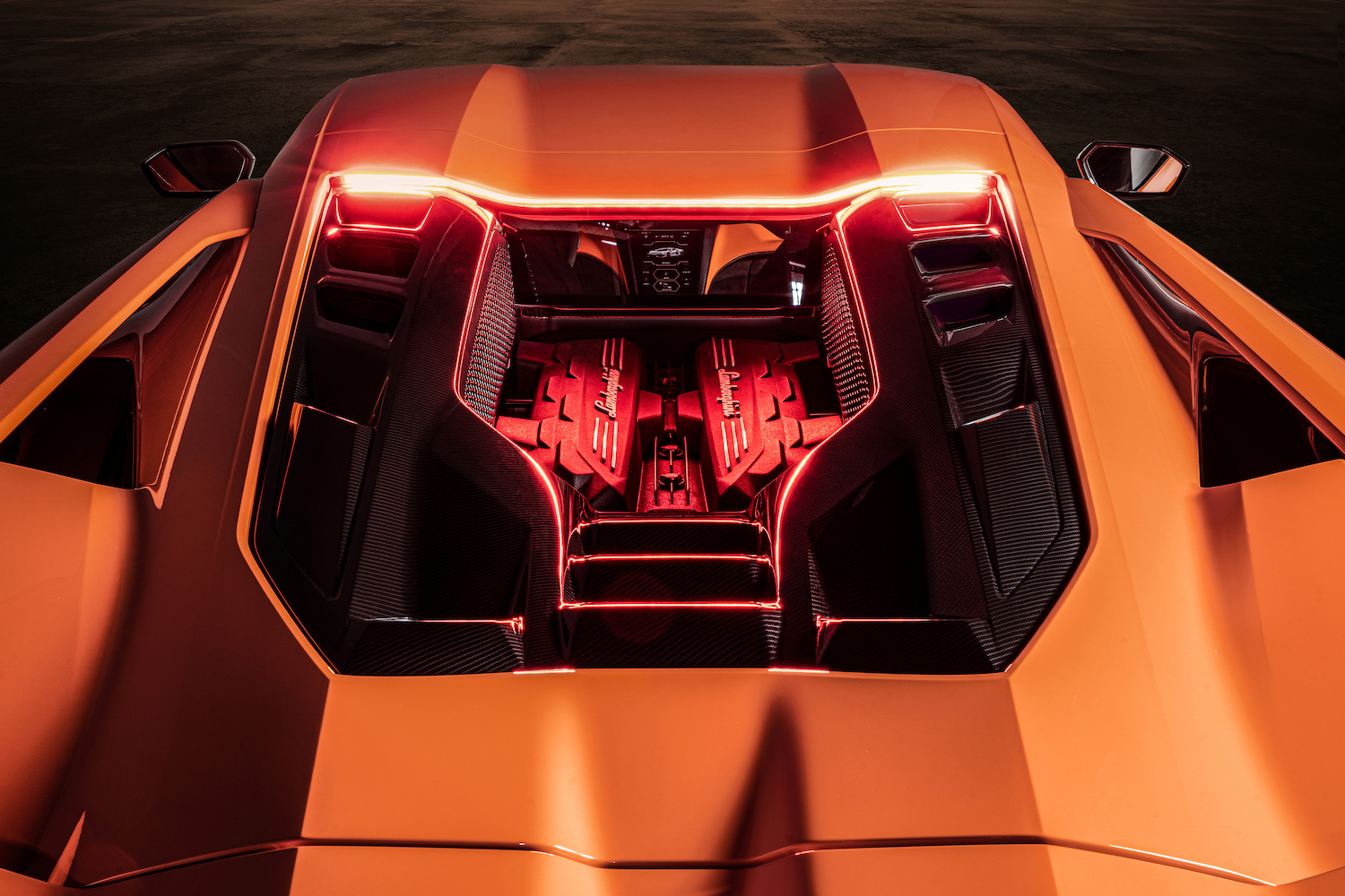 Close up of engine bay in the 2024 Lamborghini Revuelto with orange lighting.
