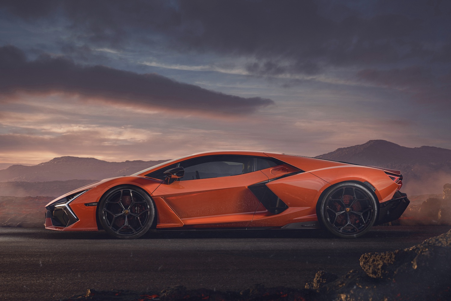 Side profile of the 2024 Lamborghini Revuelto with mountains and clouds in the back.
