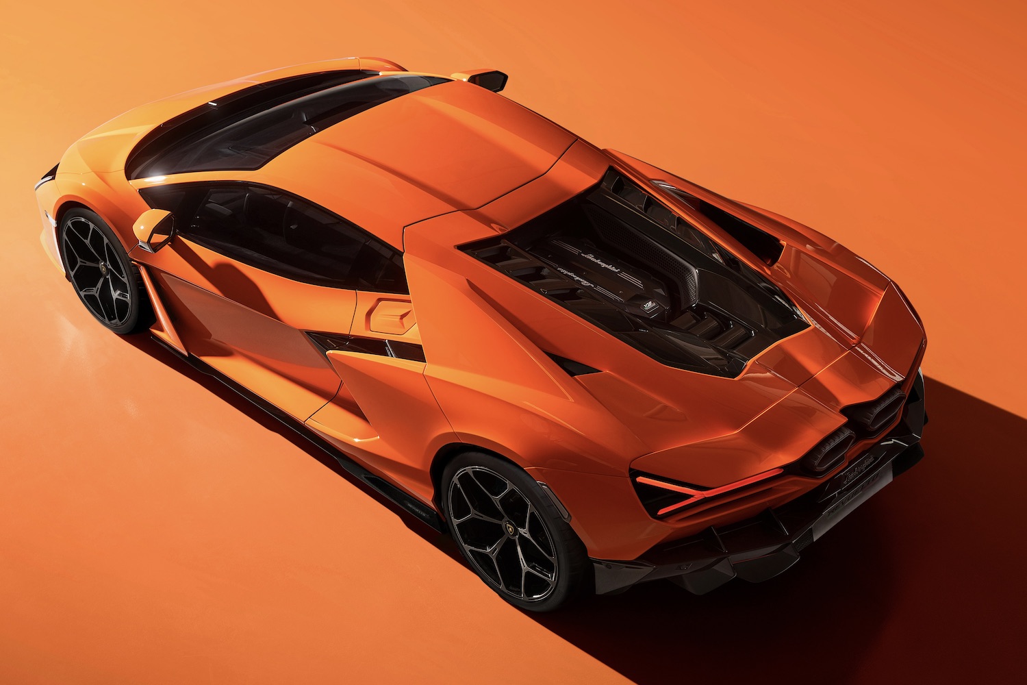 2024 Lamborghini Revuelto overhead rear end angle with an orange background.