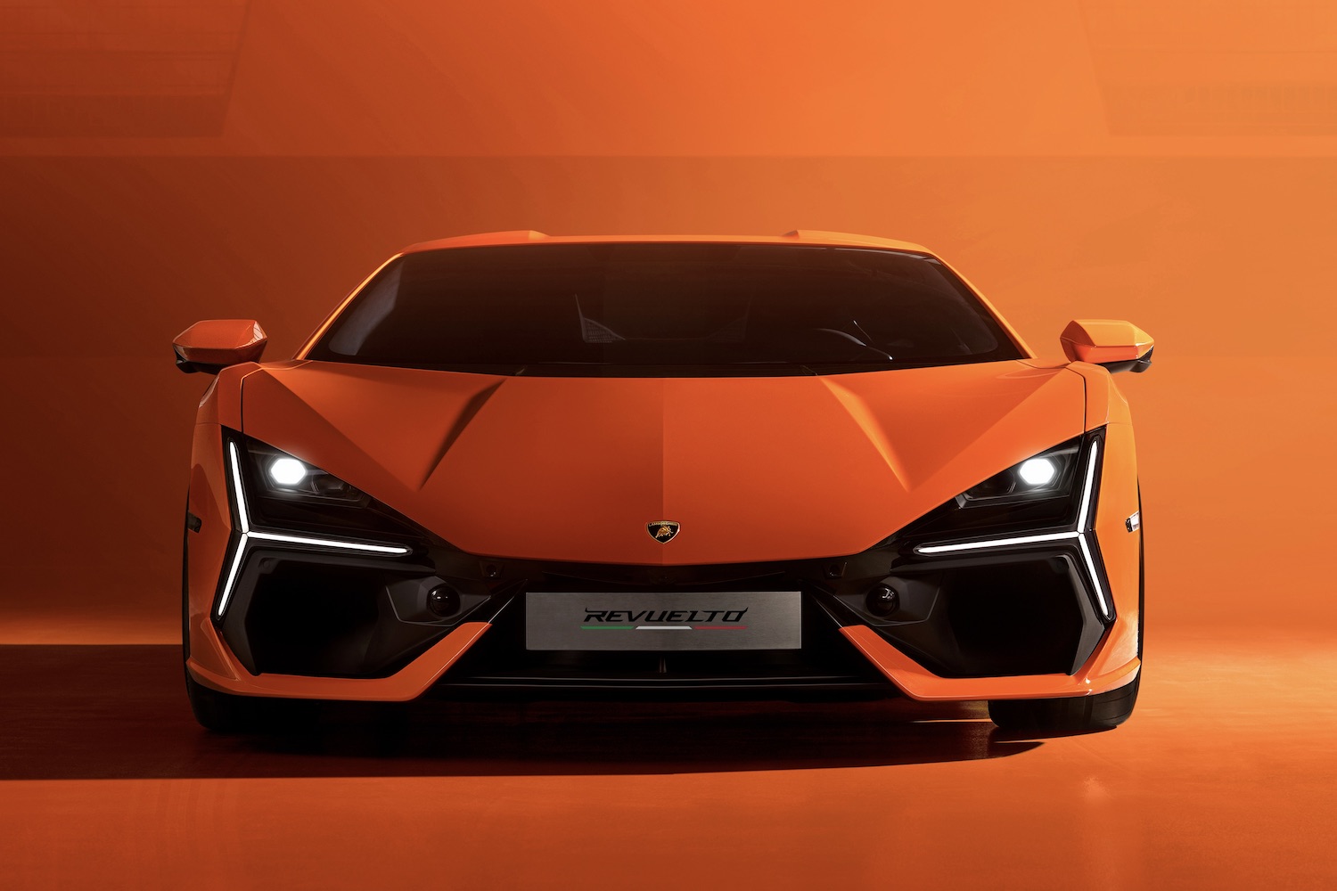 Front end close up of the 2024 Lamborghini Revuelto with an orange background.