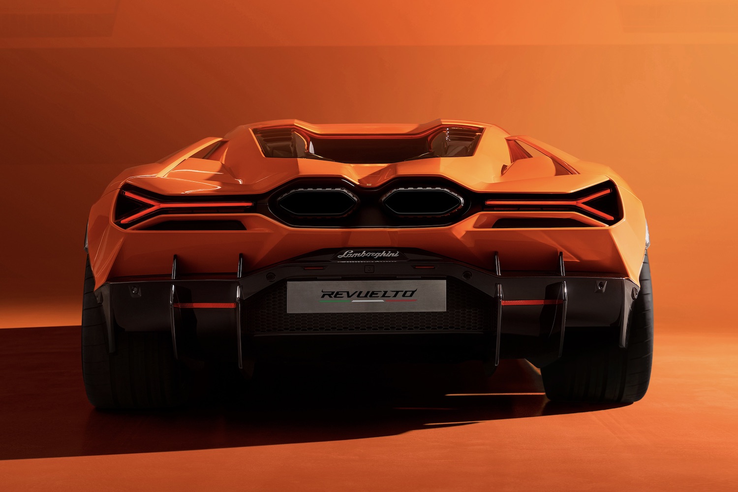 Rear end close up of the 2024 Lamborghini Revuelto with an orange background.