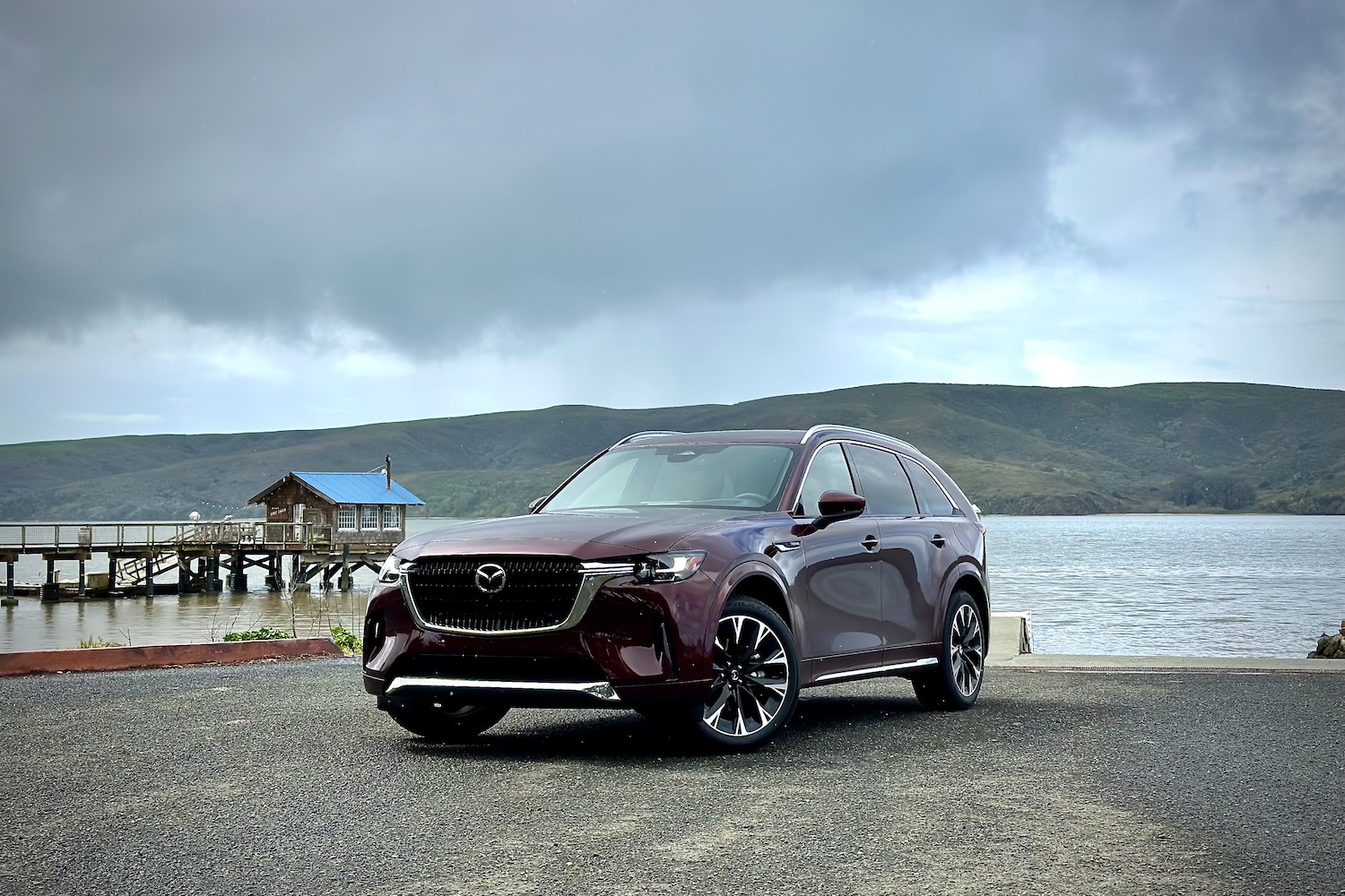 2024 Mazda CX-90 front end angle parked in front of a mountain and lake. 