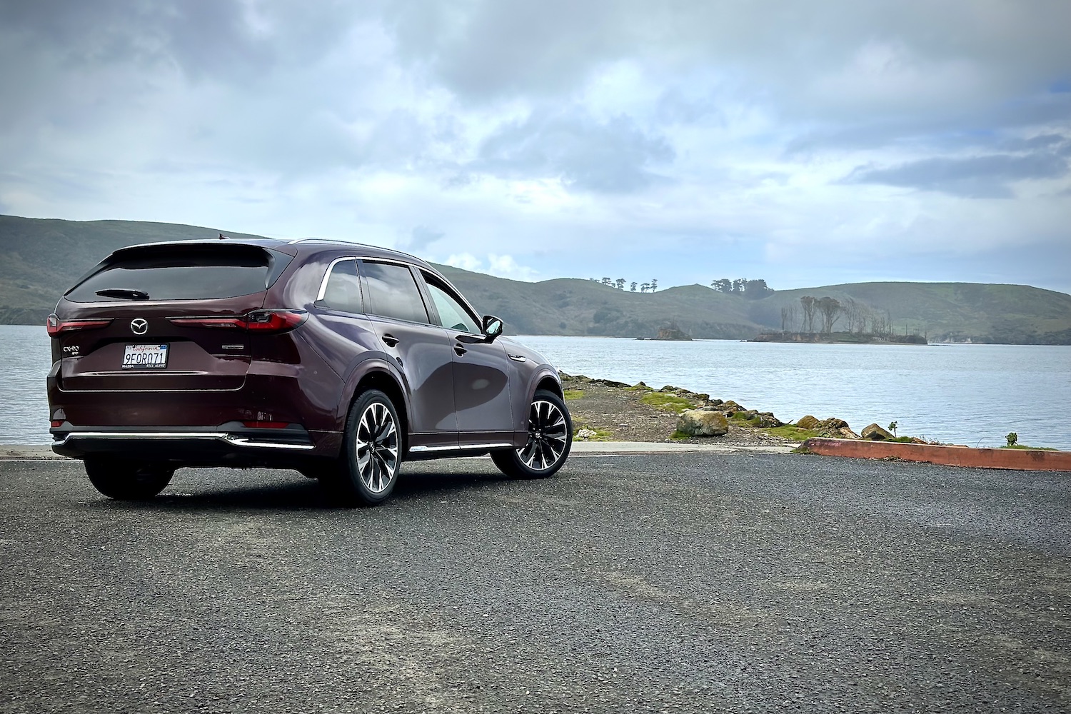 2024 Mazda CX-90 rear end angle from passenger's side parked in front of a lake.