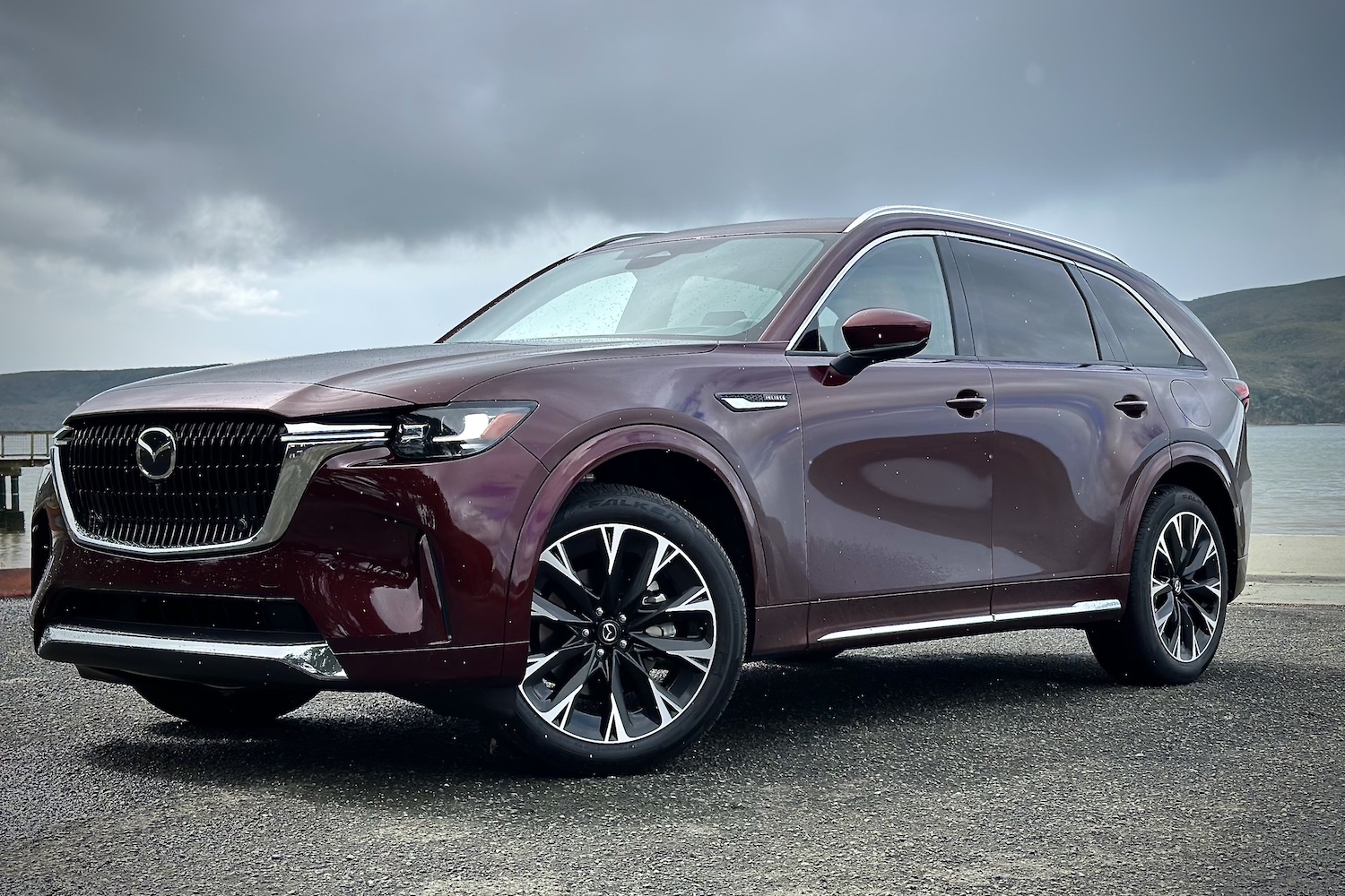 Front end angle of the 2024 Mazda CX-90 from the driver's side in front of dark clouds.