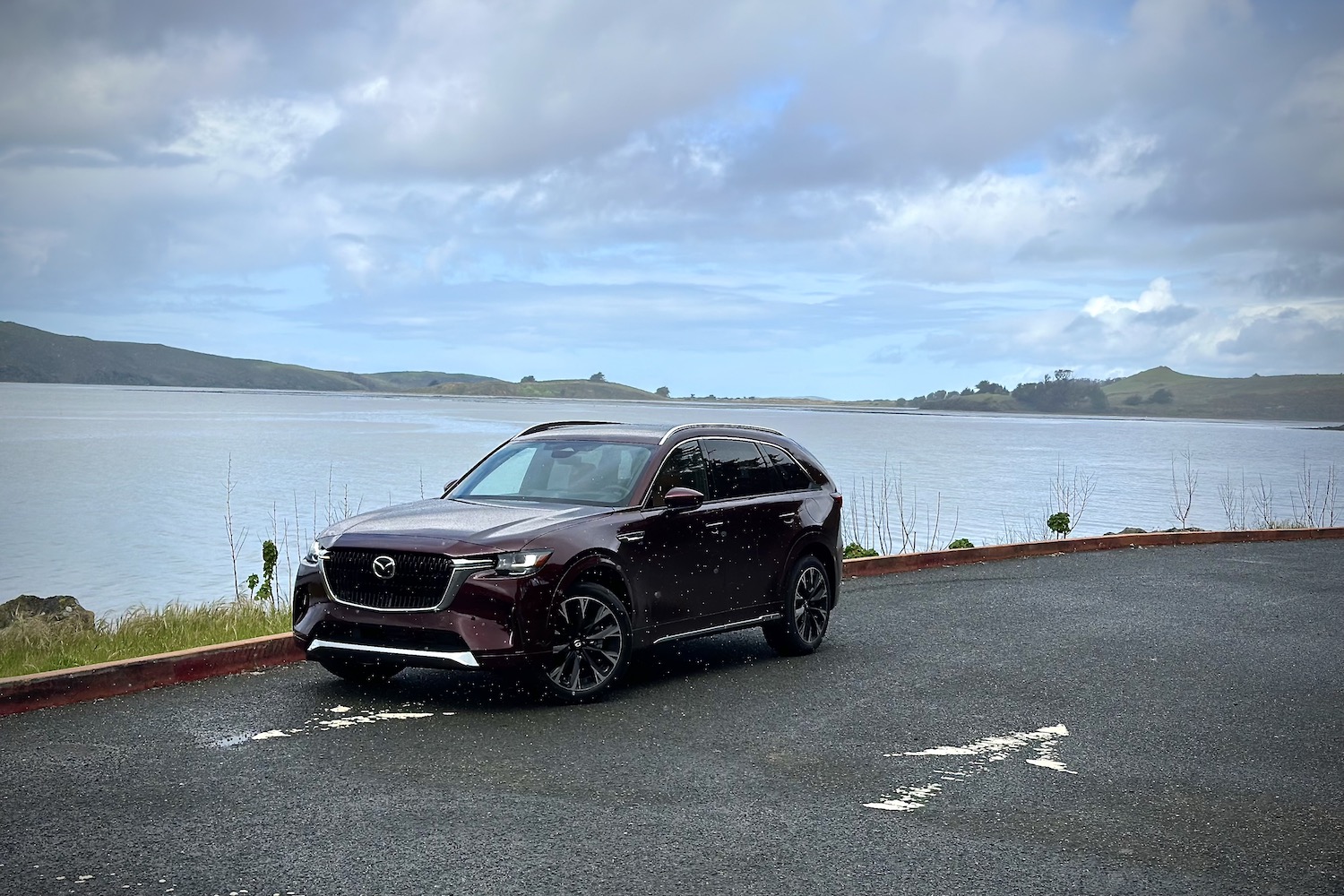 Front end angle of the 2024 Mazda CX-90 from the driver's side in front of a lake.