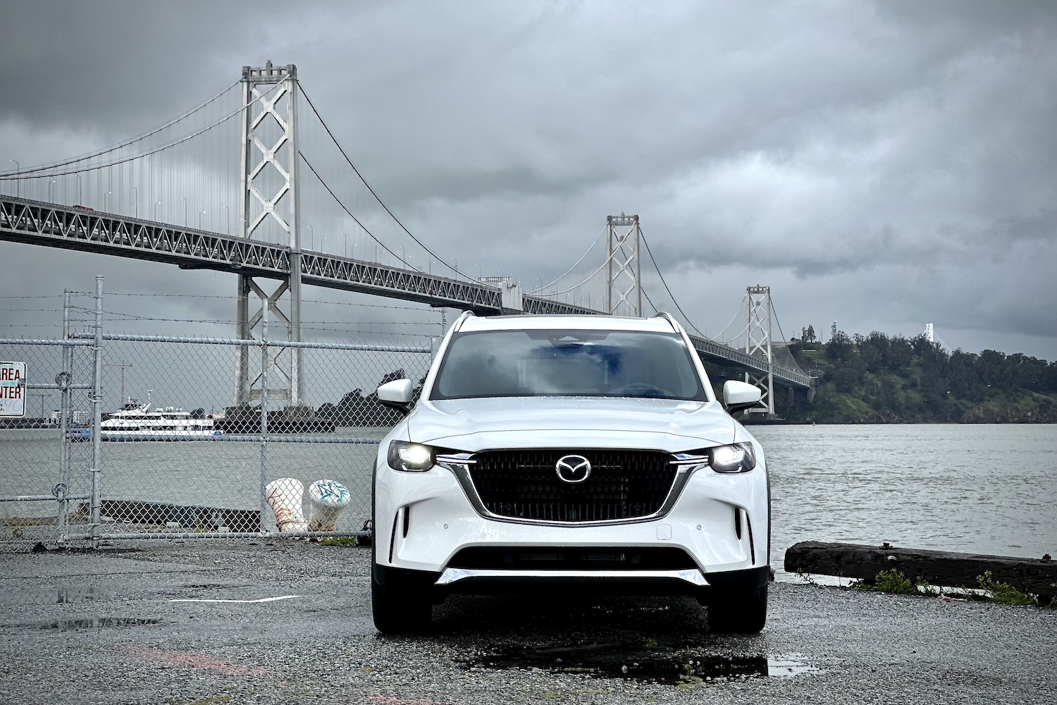 Close up of front end of the 2024 Mazda CX-90 PHEV parked in front of a bridge.