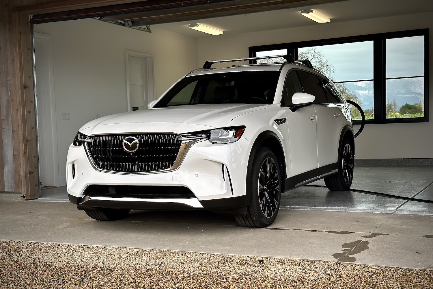 Front end angle of the 2024 Mazda CX-90 PHEV from the driver's side parked in a garage.
