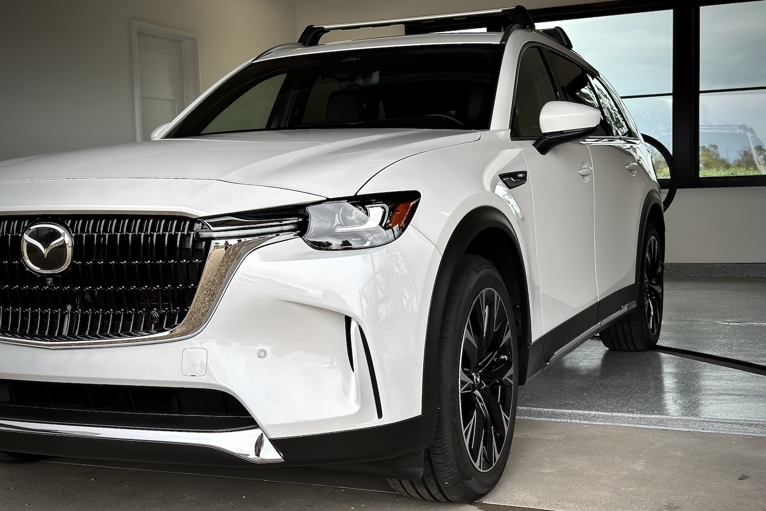 Close up of front end 2024 Mazda CX-90 PHEV from driver's side in a garage.