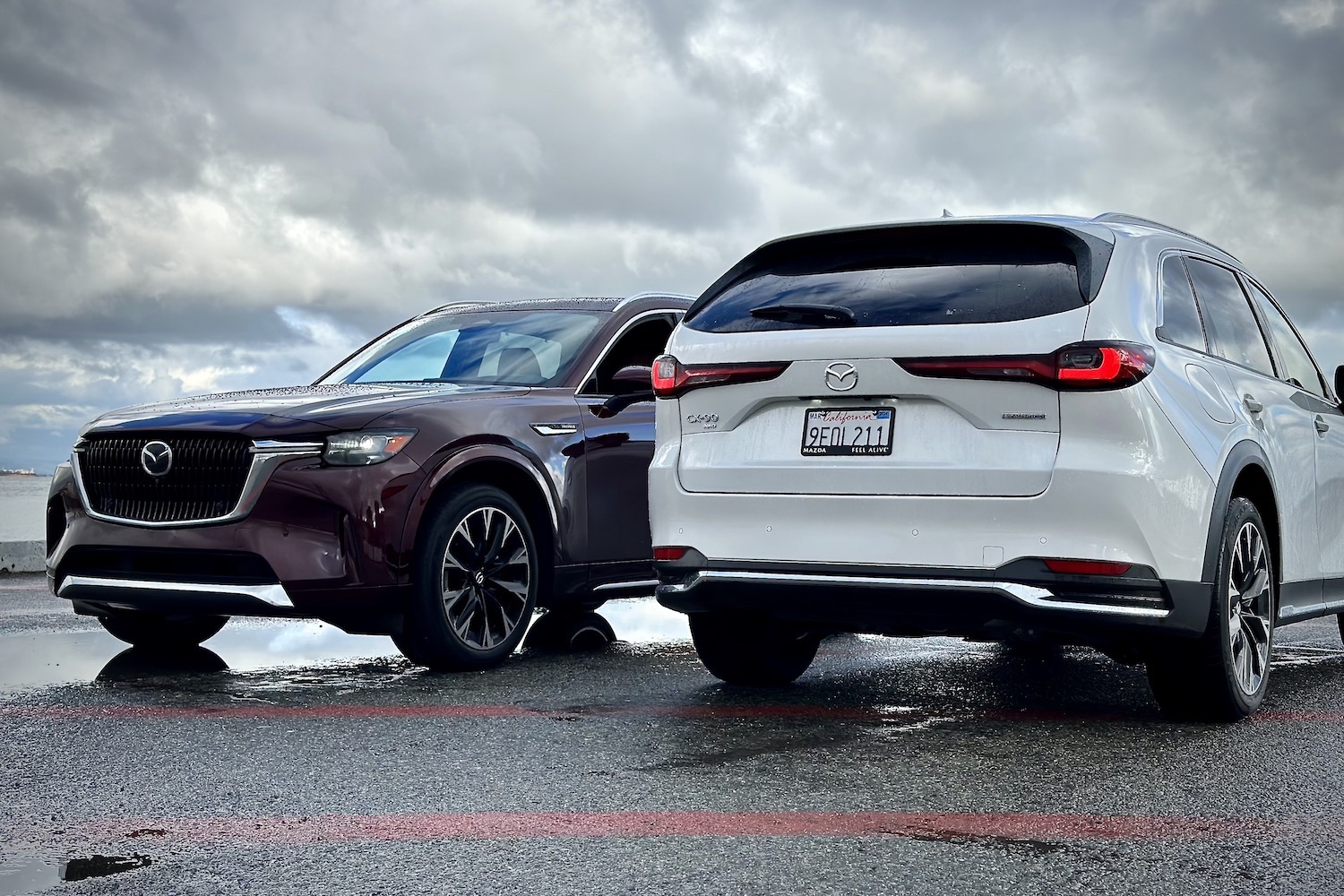 Front and rear end of the 2024 Mazda CX-90 and PHEV parked in front of dark clouds.