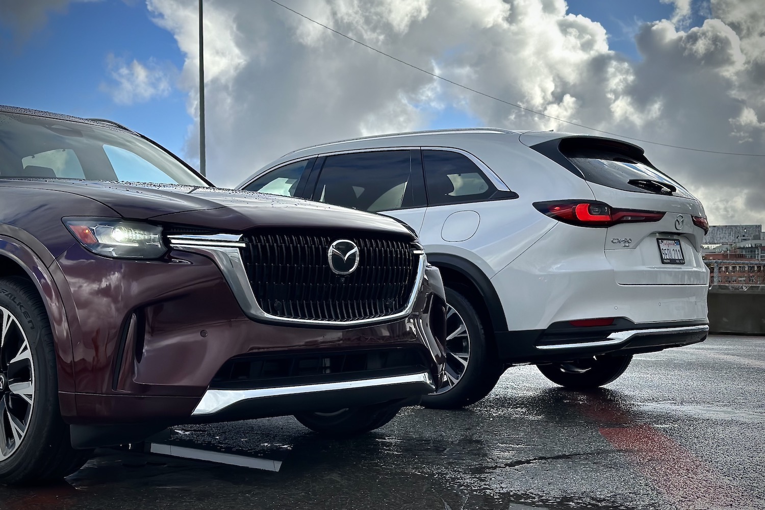 Front and rear end of the 2024 Mazda CX-90 and PHEV parked in front of dark clouds.