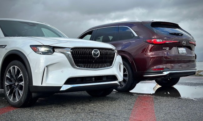 Front and rear end of the 2024 Mazda CX-90 and PHEV parked in front of dark clouds.