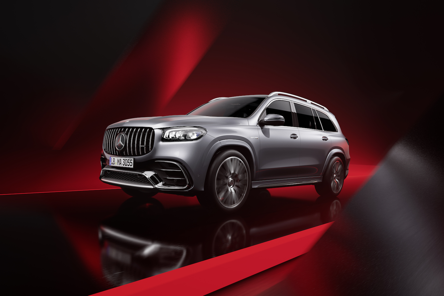 Front end angle of the 2024 Mercedes-Benz GLS AMG 63 from the driver's side in front of a red and black background.