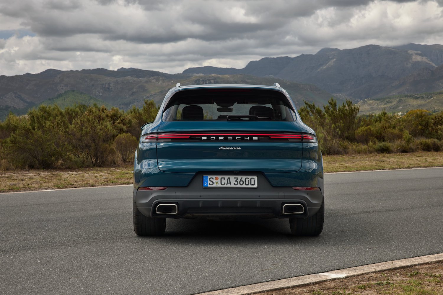 Close up of rear end of the 2024 Porsche Cayenne parked in front of mountains.