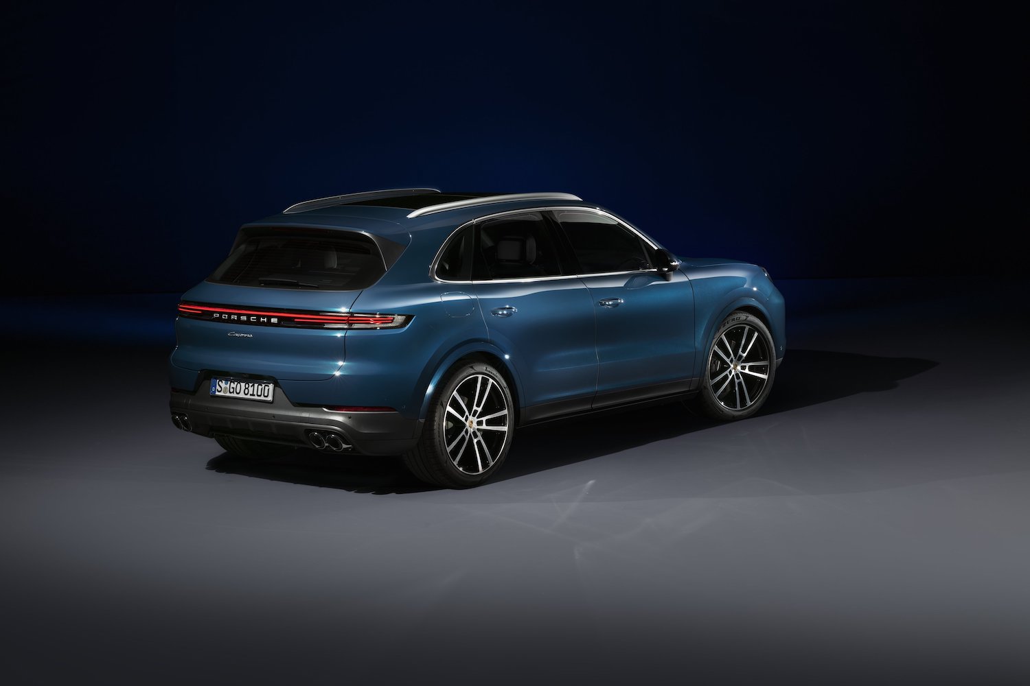 Rear end angle of the 2024 Porsche Cayenne parked in a dark studio from passenger's side.