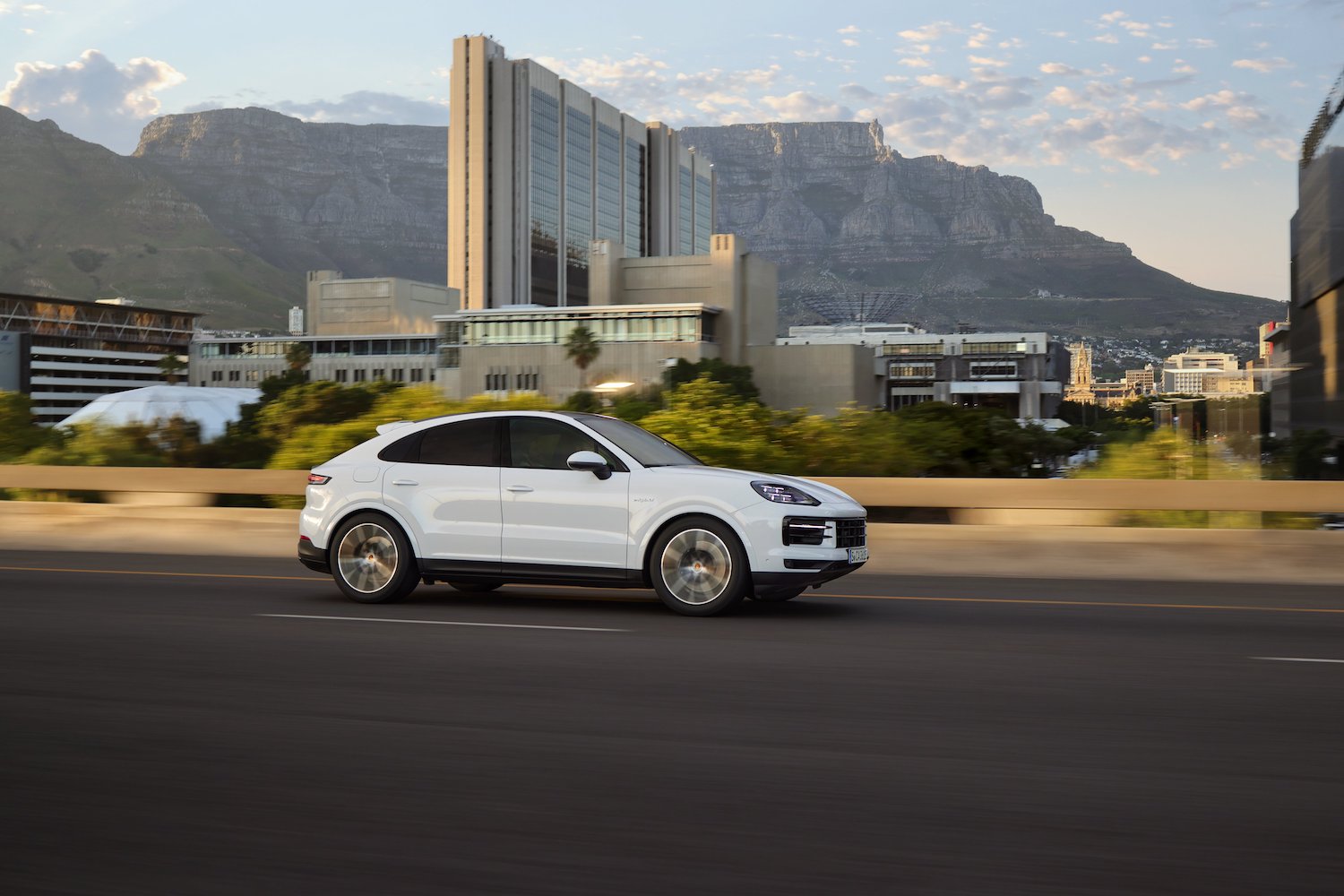 2024 Porsche Cayenne E-Hybrid side profile of SUV driving down the road.