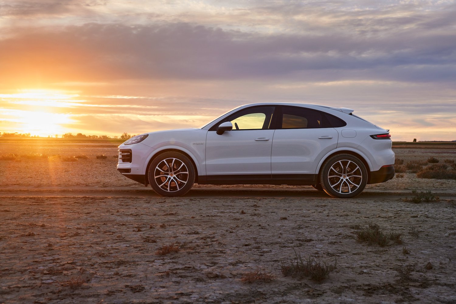 2024 Porsche Cayenne E-Hybrid side profile parked in front of a sunset.
