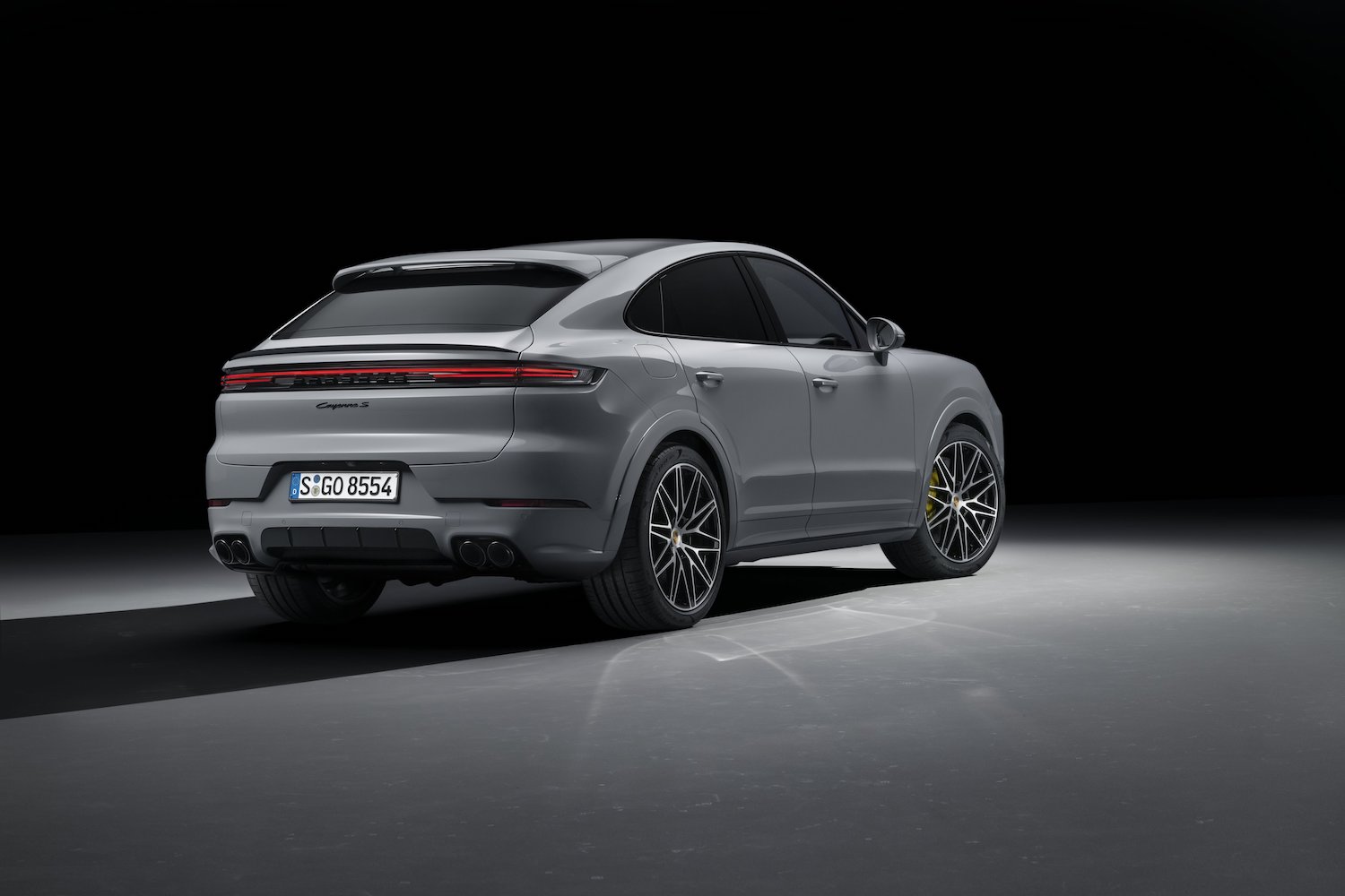 Rear end angle of the 2024 Porsche Cayenne S from the passenger's side parked in a dark studio.
