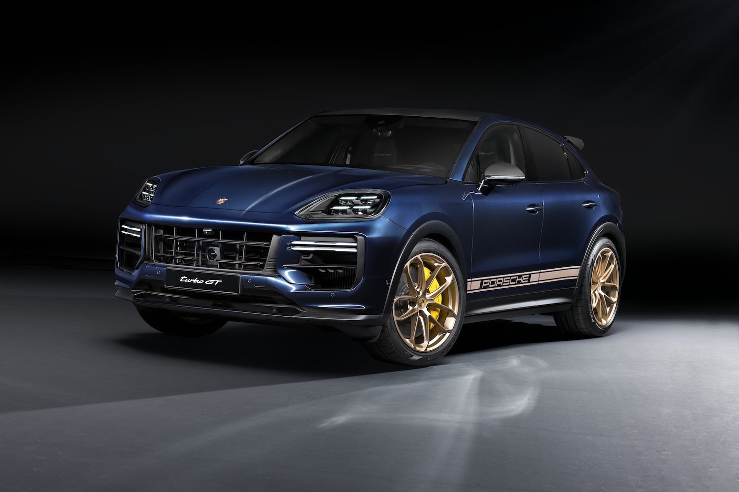 Front end angle of the 2024 Porsche Cayenne Turbo GT from the driver's side in a dark studio.