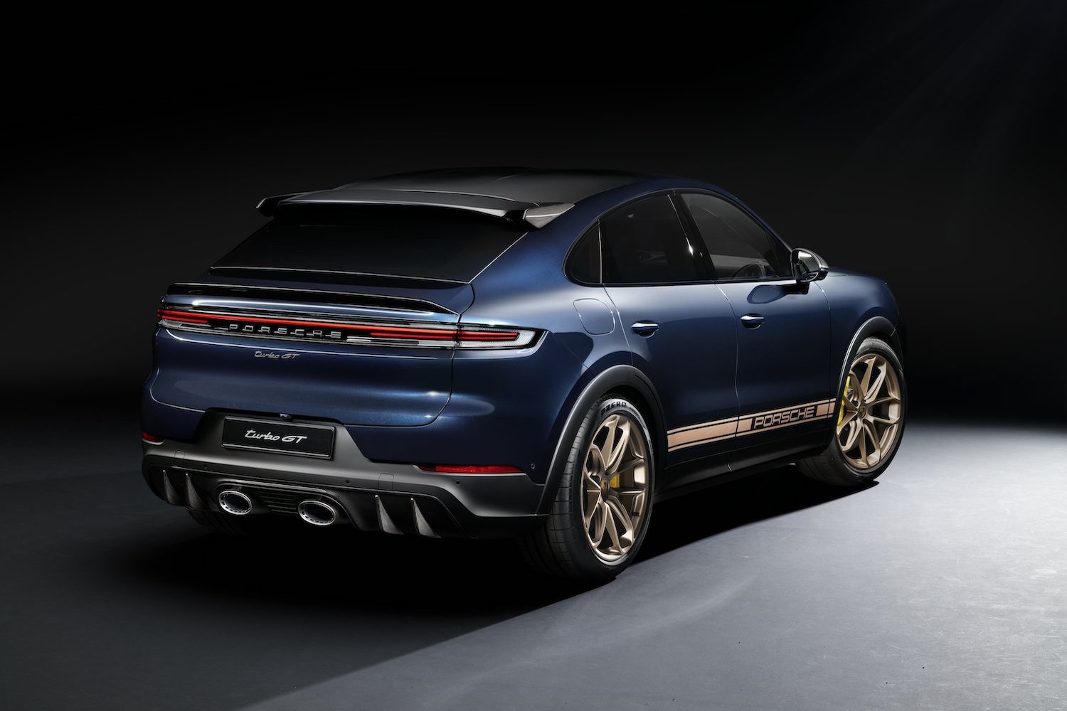 2024 Porsche Cayenne Turbo GT rear end angle from passenger's side in a dark studio.