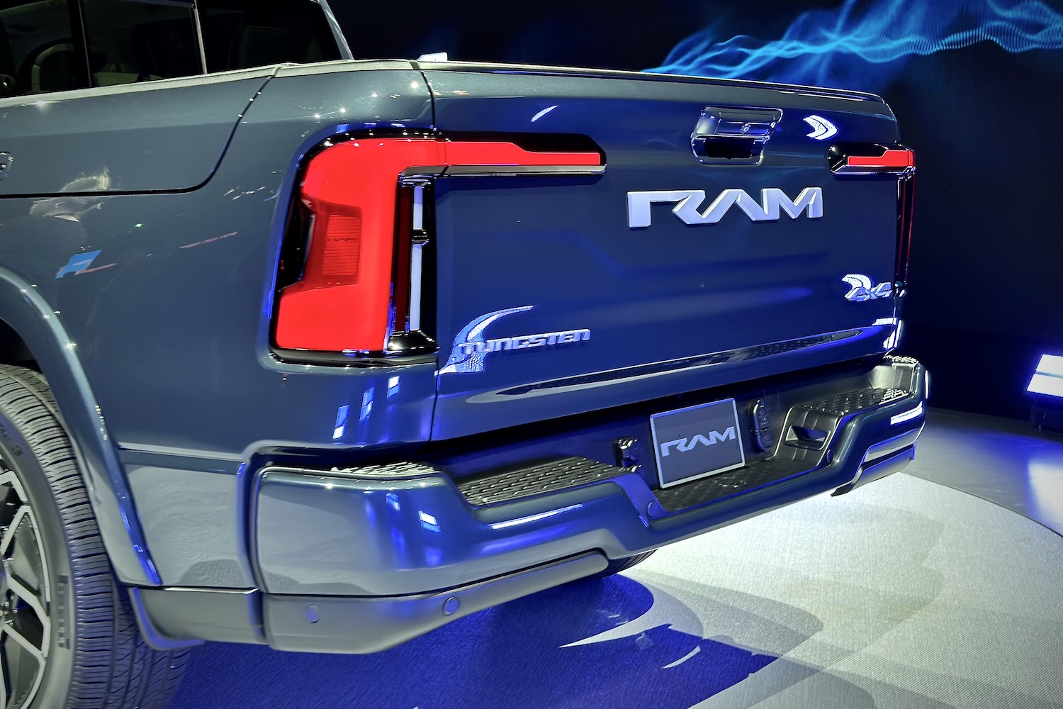 Rear end angle of the 2025 Ram 1500 REV from driver's side parked on a stage.