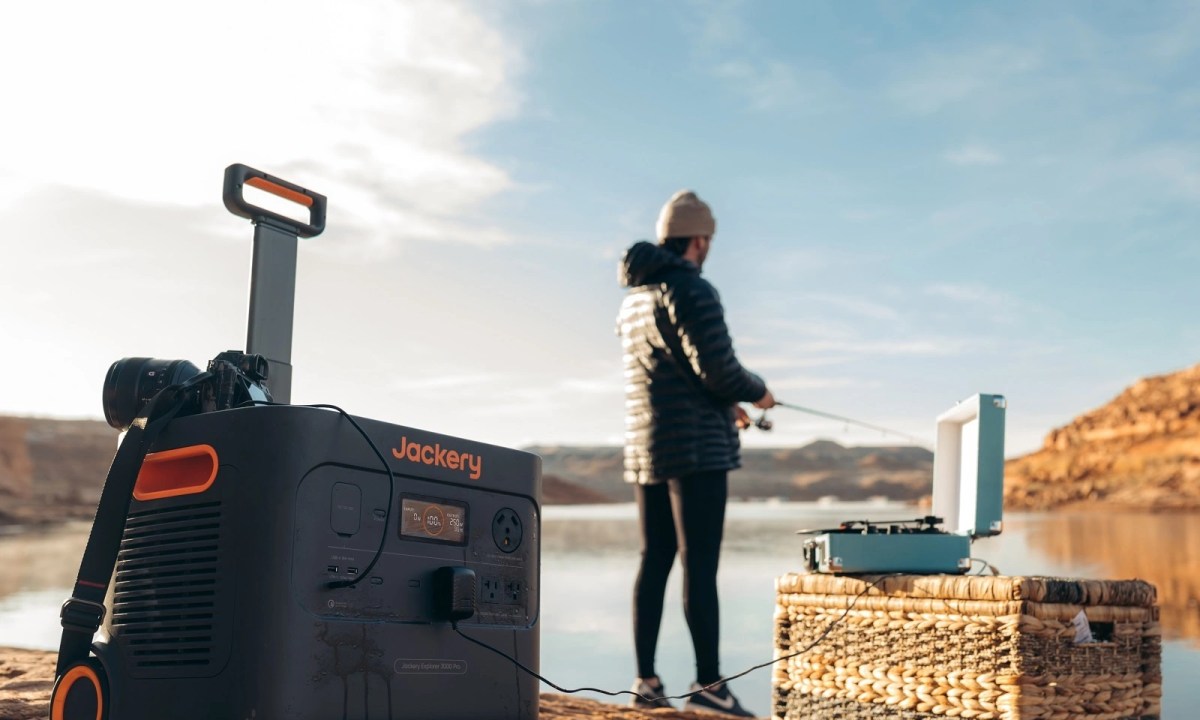 Person using Jackery portable power station outdoors while fishing