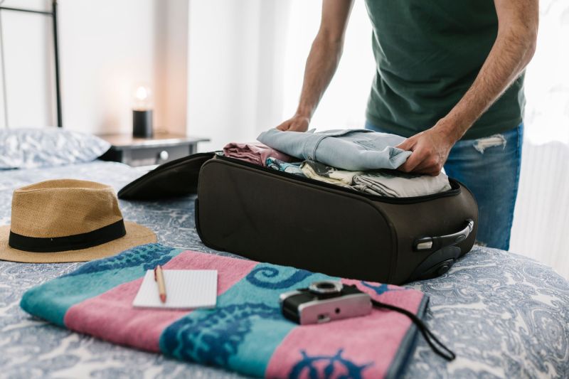 Man packing suitcase on a bed