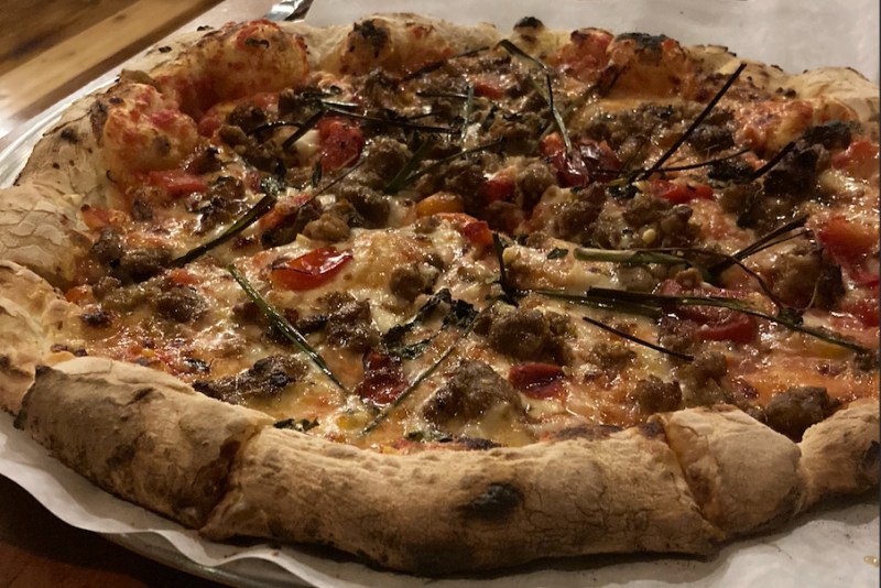 Sausage pizza with roasted peppers, wild spring onions, and herbs.