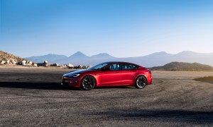 Tesla Model S side profile from front end parked in front of mountains with a blue sky.