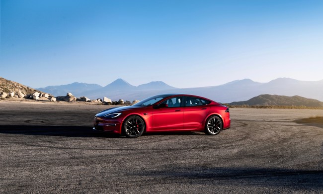 Tesla Model S side profile from front end parked in front of mountains with a blue sky.
