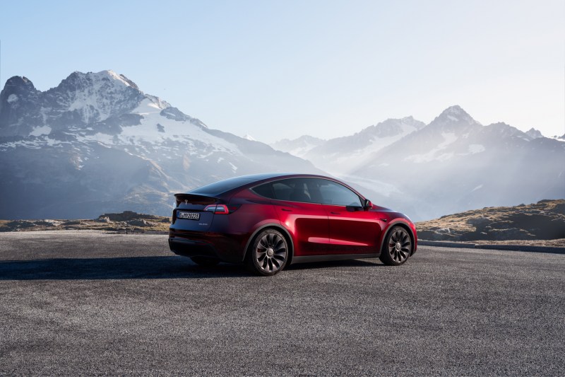 Tesla Model Y rear end angle from passenger side parked in front of mountains.