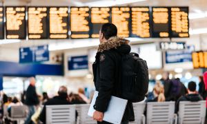 Traveler carrying a laptop checking flight schedule